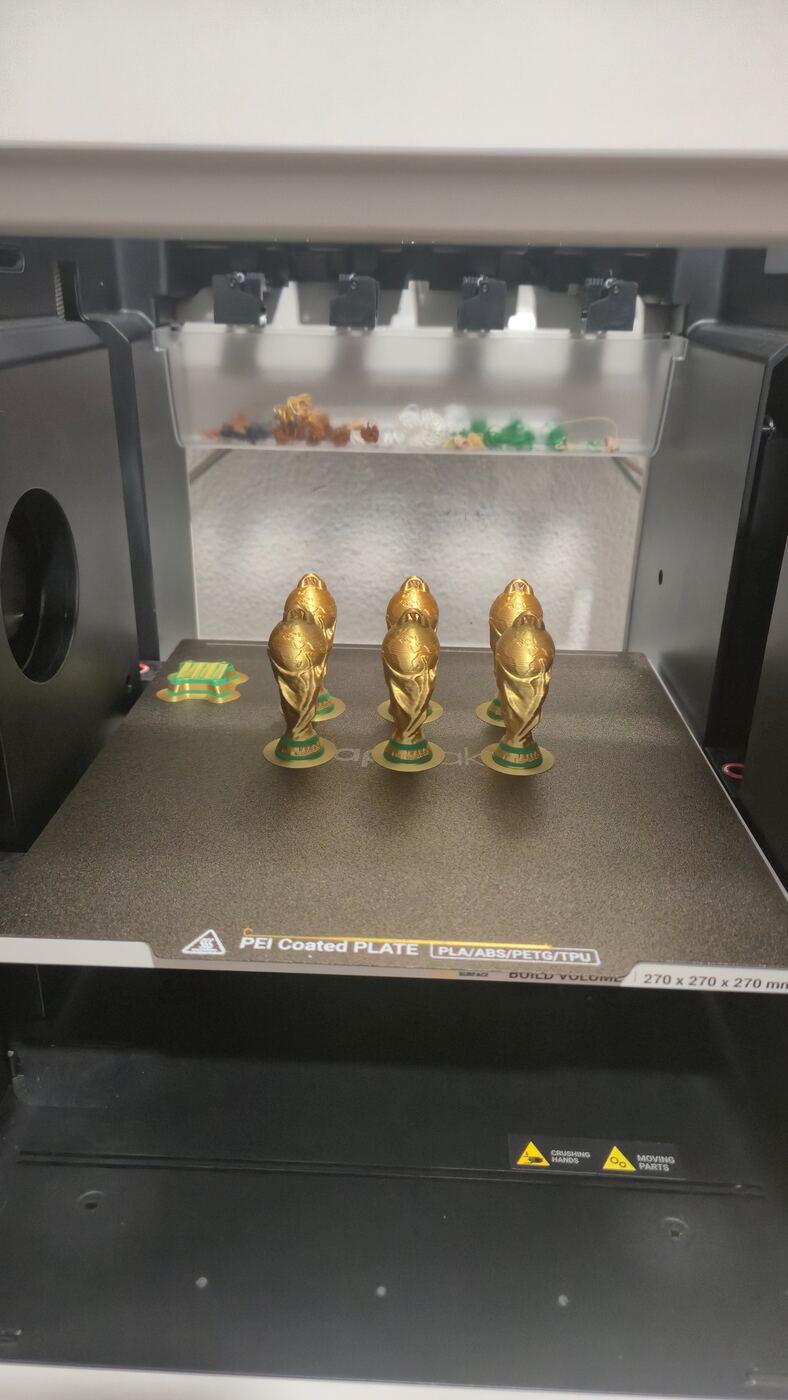 Impresora 3D fabricando piezas doradas